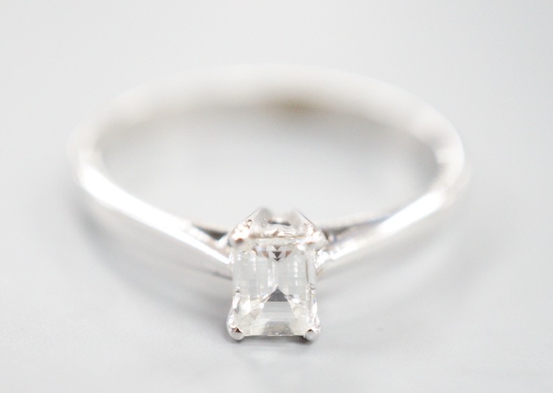 A modern 18ct white metal and solitaire emerald cut diamond set ring, size K, gross weight 2 grams